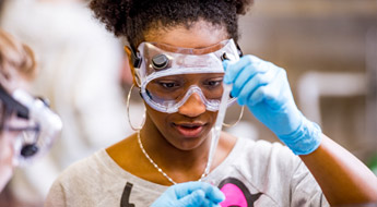Female student measures liquid with pipette.