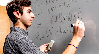 Male student writes on white board