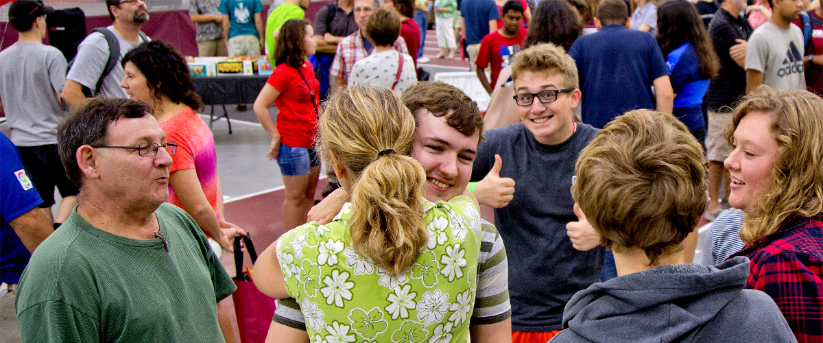 A mom hugs her son as he starts his freshman year at Rose-Hulman while the rest of the family smiles and shows their support. 