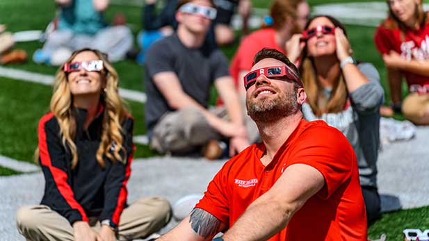 People looking at the solar eclipse on the Rose-Hulman football field.