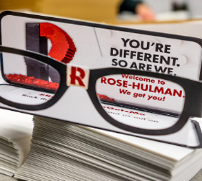 Image shows the black-rimmed paper “nerd glasses” sent to admitted students with red R for Rose-Hulman on the glass’s bridge and a card reading “You’re different. So are we.”