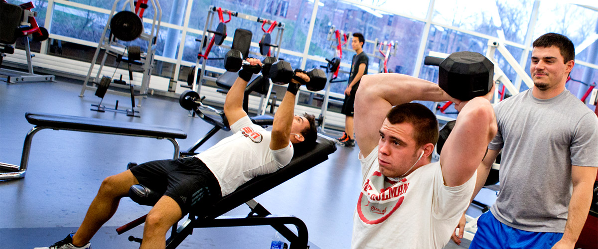 Image shows male students lifting weights inside the SRC weight room.