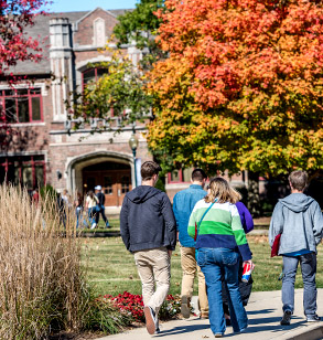 Image shows students walking on campus with fall colors in the background and Moench Hall also in the distance.
