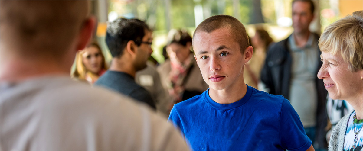 A high school student listens to facts about Rose-Hulman in a room full of other students and parents. 