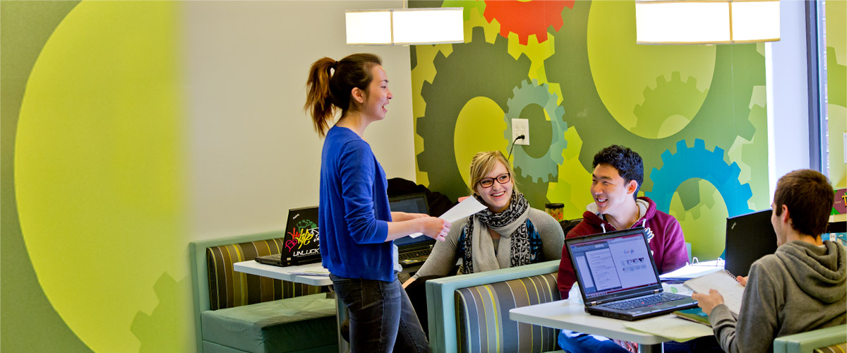 Rose-Hulman students smiling and talking inside the small snack and coffee shop inside the Logan Library