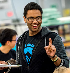 !Smiling male student holding up finger to indicate the number one.