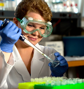 Student extracting a fluid from a glass beaker in a biology laboratory. 