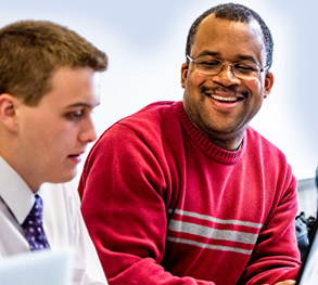 Faculty member smiling and talking with student