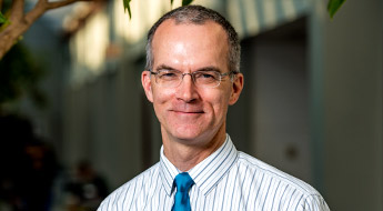 !A smiling Dr. James Mayhew standing outdoors on the Rose-Hulman campus.