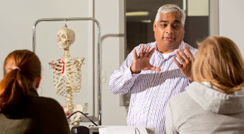 A professor lectures in a biomedical engineering lab as students listen.