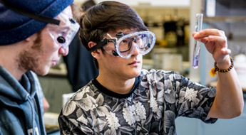 Two male students examine liquid in a test tube.