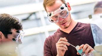 Male student scoops dry chemical ingredient for experiment.