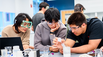Three male students work in a chemistry lab. 