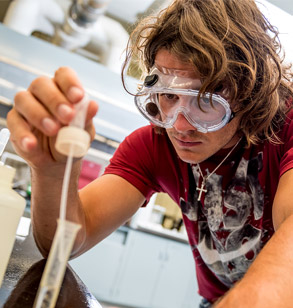 Male student uses dropper to add liquid to test tube.