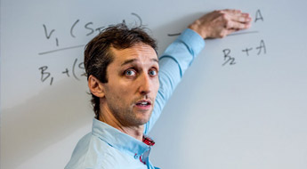 Professor working a problem on a white board.