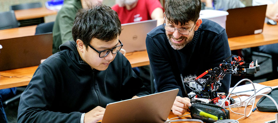 Student working on robot with professor