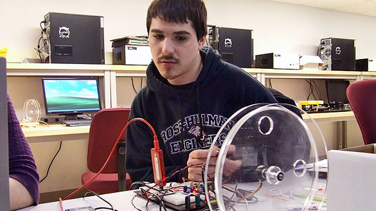 Male student tests device in electrical engineering lab.
