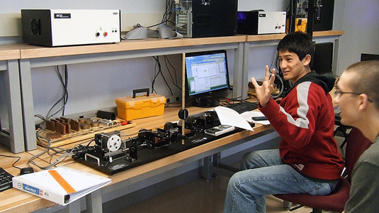 Male student presses button on electronic equipment.