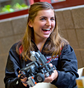 Smiling female student holds small robot in her hands.
