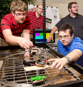 Two male students test the function of a project-in-process for a local children’s museum.