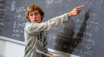 Student pointing to equation on a blackboard.