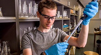 Student putting fluid into a test tube.