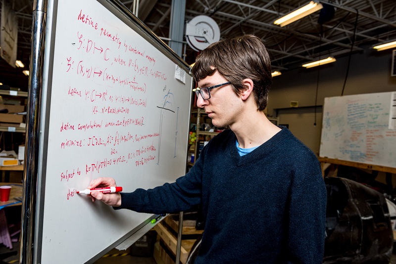 Student pointing to equation on a blackboard.