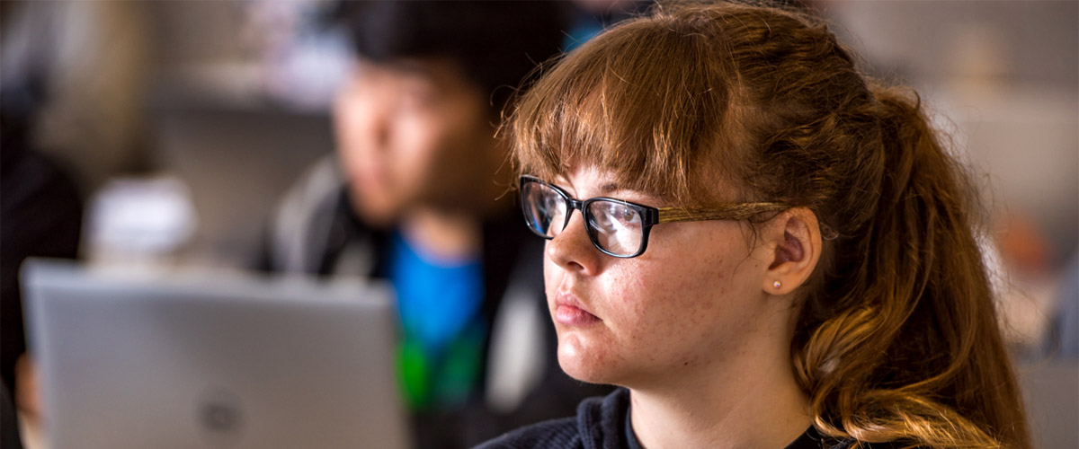 Female student in a classroom listening to a lecture.