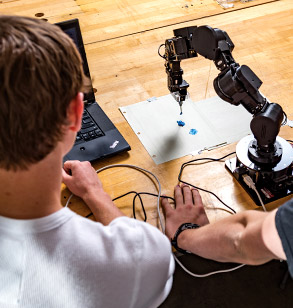 Students use robotic arm to apply paint to paper.