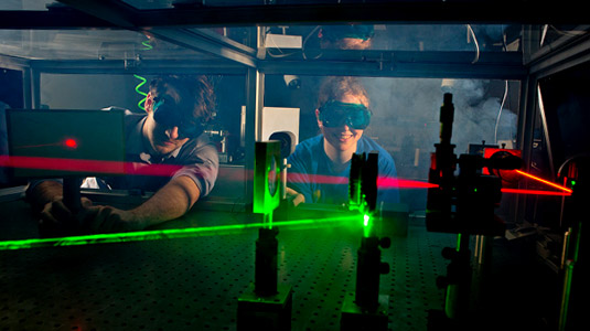 Two students experiment with lasers in optics lab.
