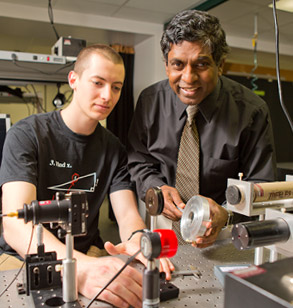 Dr. Joenathan works with male student in optics lab.