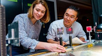 Female instructor points to laptop in electrical engineering lab.