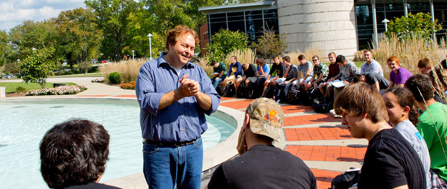 Dr. Kukral teaches a class outside near the Flame of the Millennium sculpture.