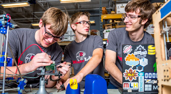 Three male students work on projects in the Branam Innovation Center.