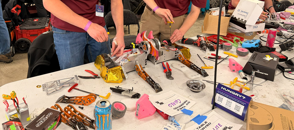 Two students work on a robot on a table.