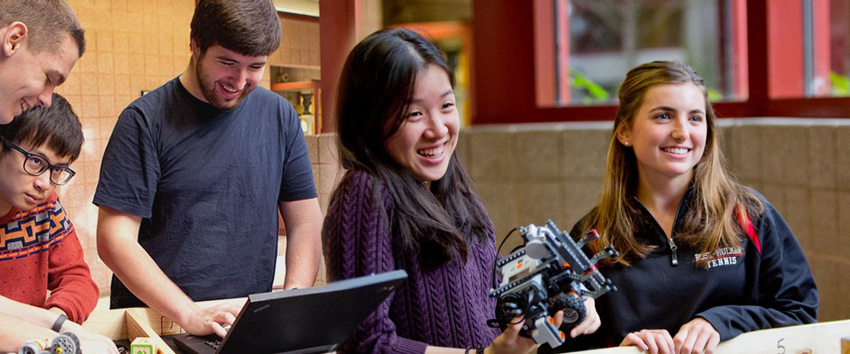 Smiling male and female students work on robotics project.