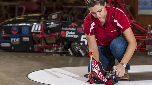 Female student places NXP cup robot on its track.