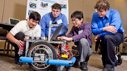 Students use laptop to make programming changes for large robotic device.