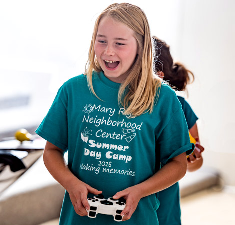 A smiling young girl holds an electronic controller