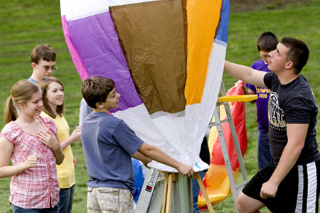 Students hold tissue paper hot air balloon as it is inflated.