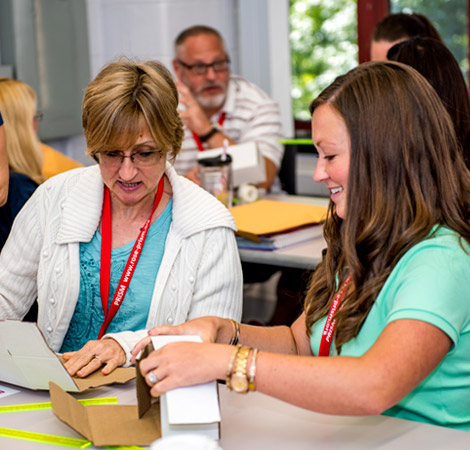 Two teachers work together on hands-on activity at PRISM summer workshop.