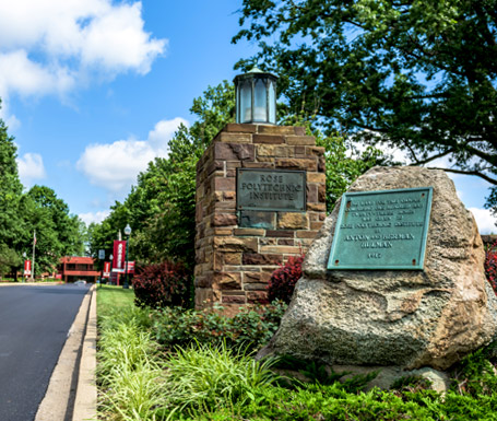 Stone lamp post and large rock with plaque at the front gate of Rose-Hulman.