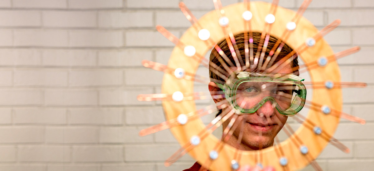 Young man wearing glasses looks through a circular object