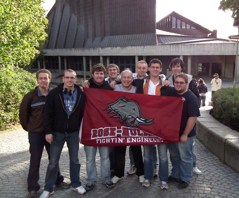 Students holding a Rose-Hulman “Fightin’ Engineers” flag outside a partner university in Europe.
