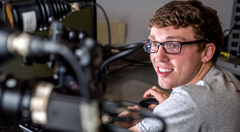 !A male student smiling and working on an experiment inside the Orthopaedic Biomedical Engineering Lab