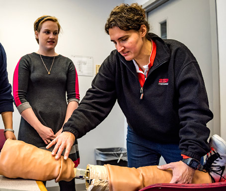 Professor Renee Rogge handling a model of a human leg used in medical training.
