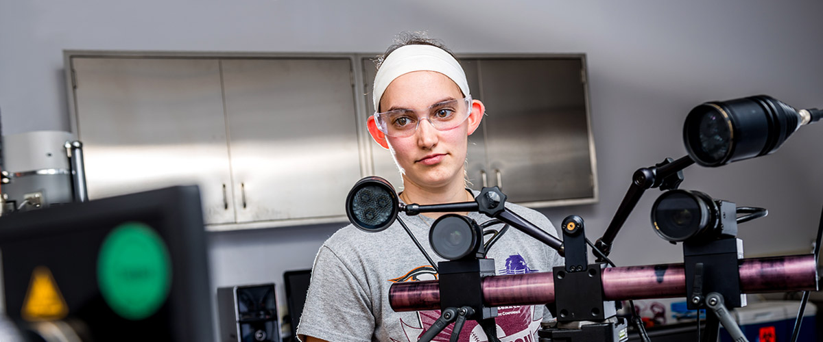 Female student reads a computer monitor while working inside the Orthopaedic Biomedical Engineering lab.