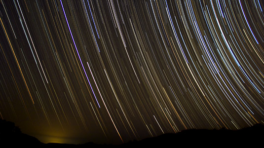Multi-colored star trails running through the night sky.