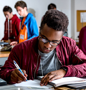 Male student writing on paper.