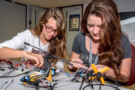 Two female Catapult students working on a remote flying device project.